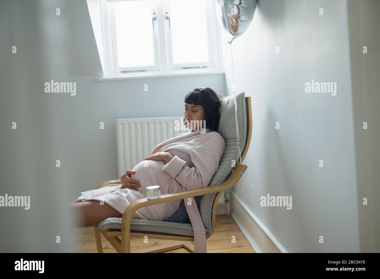 Tired pregnant woman napping in bathrobe Stock Photo