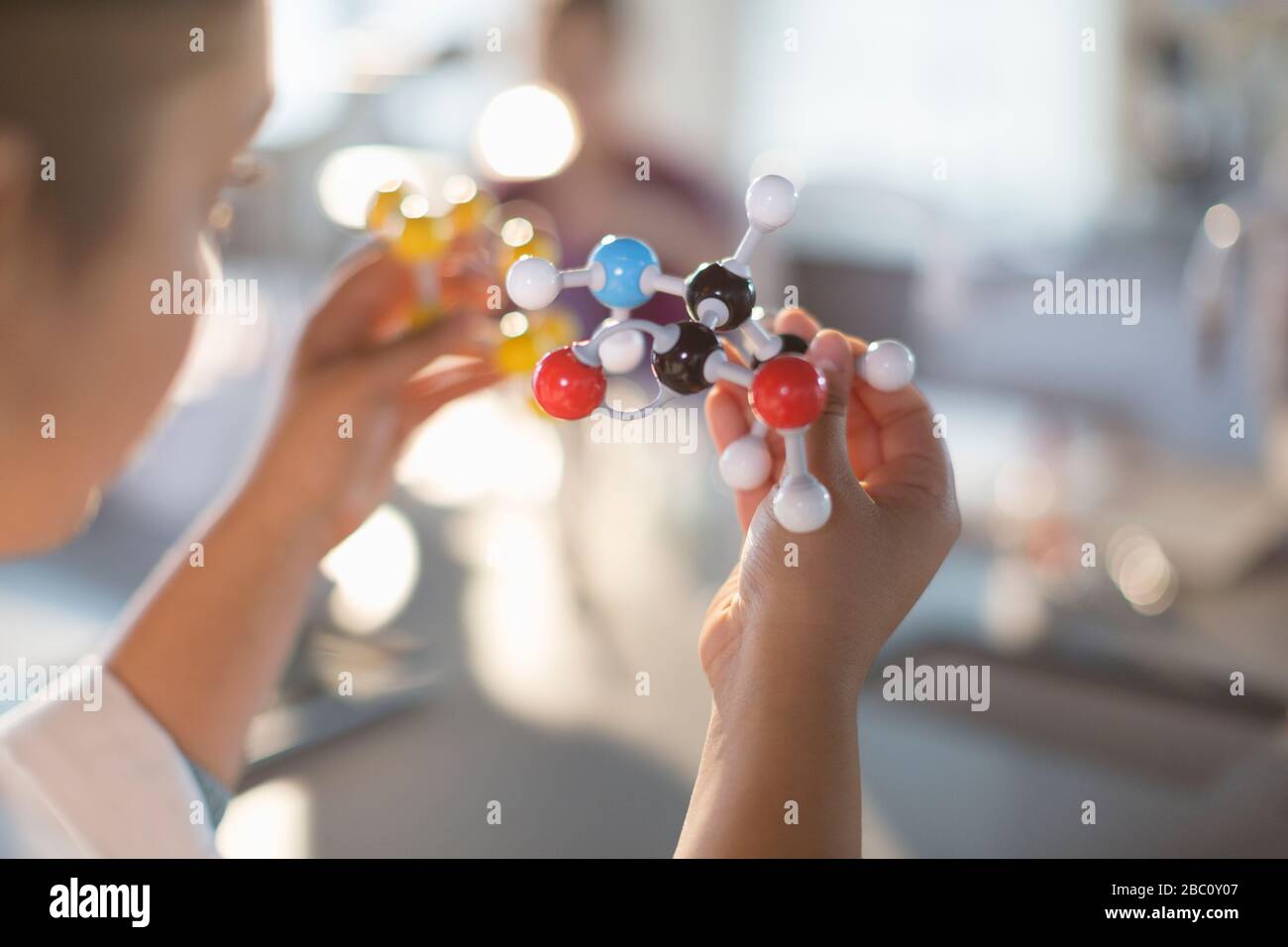 Curious girl student holding molecule model in classroom Stock Photo