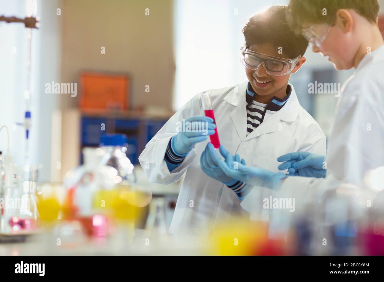 Boy students conducting scientific experiment, examining liquid in test