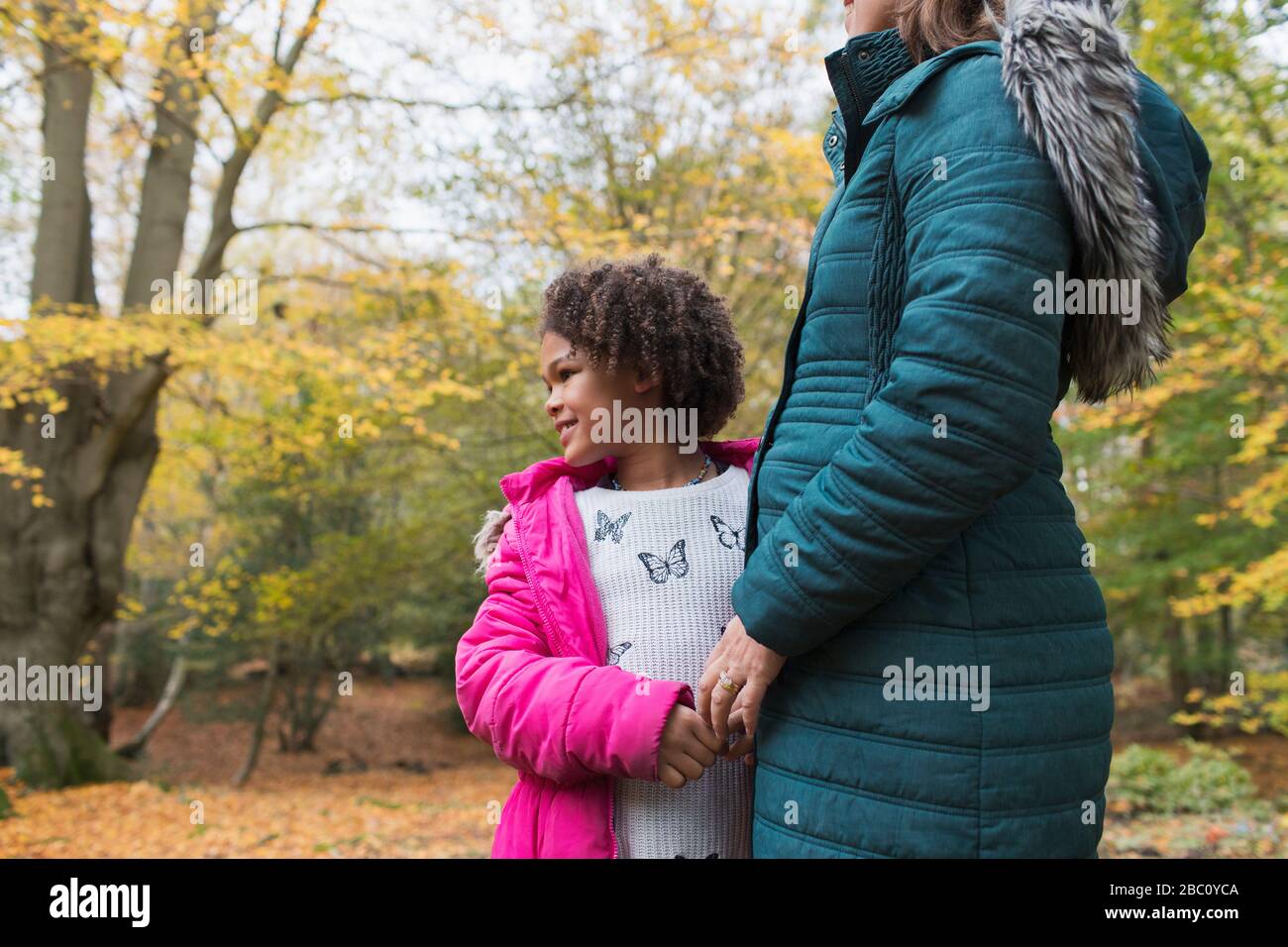 Happy daughter holding hands with mother in autumn woods Stock Photo