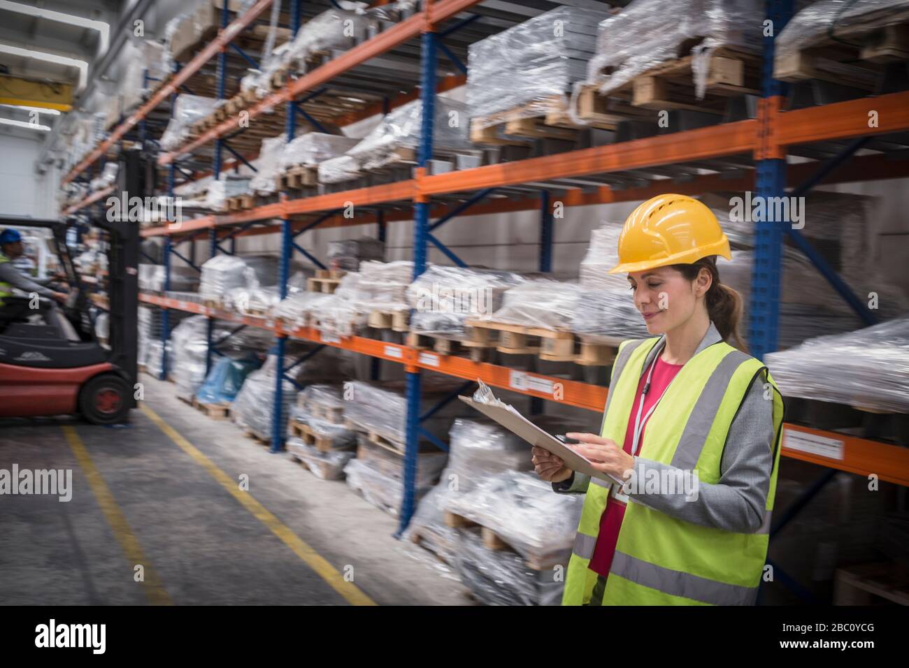 Female worker with clipboard checking inventory in warehouse Stock Photo