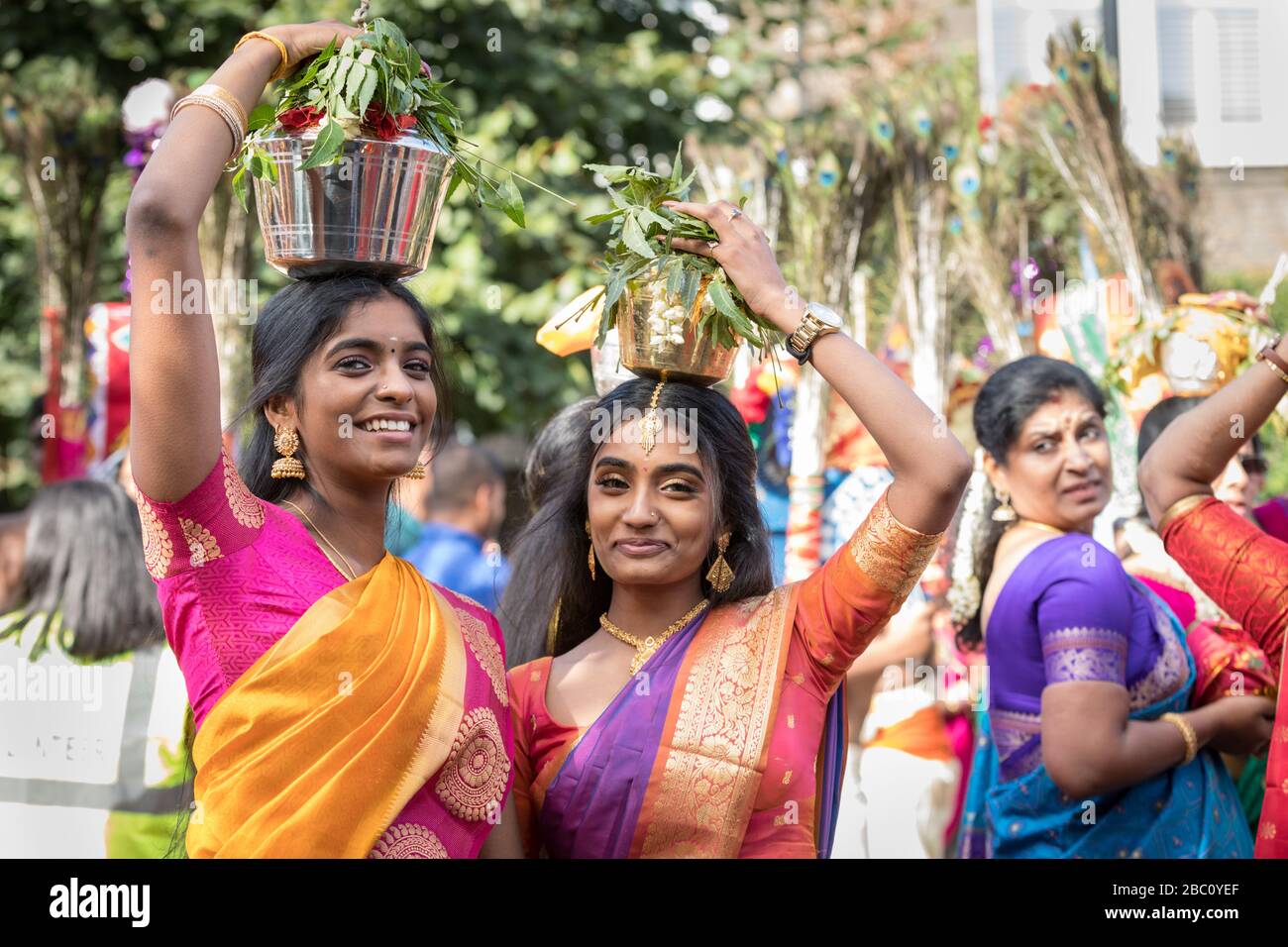 Young Hindu  women in sari, smiling as they participate in a  Chariot Festival procession, carrying offering on her head Stock Photo