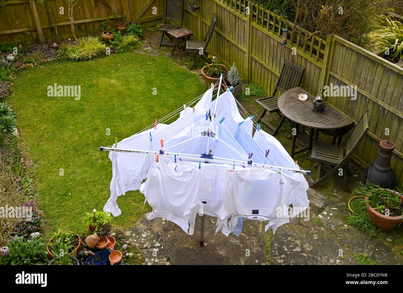 White mens shirts hanging on a rotating washing line during in the wind in back garden UK Stock Photo
