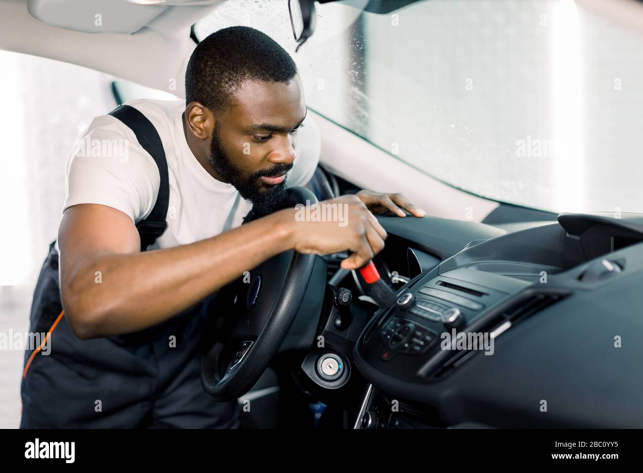 Car detailing and car wash concept. Young black man, car wash worker
