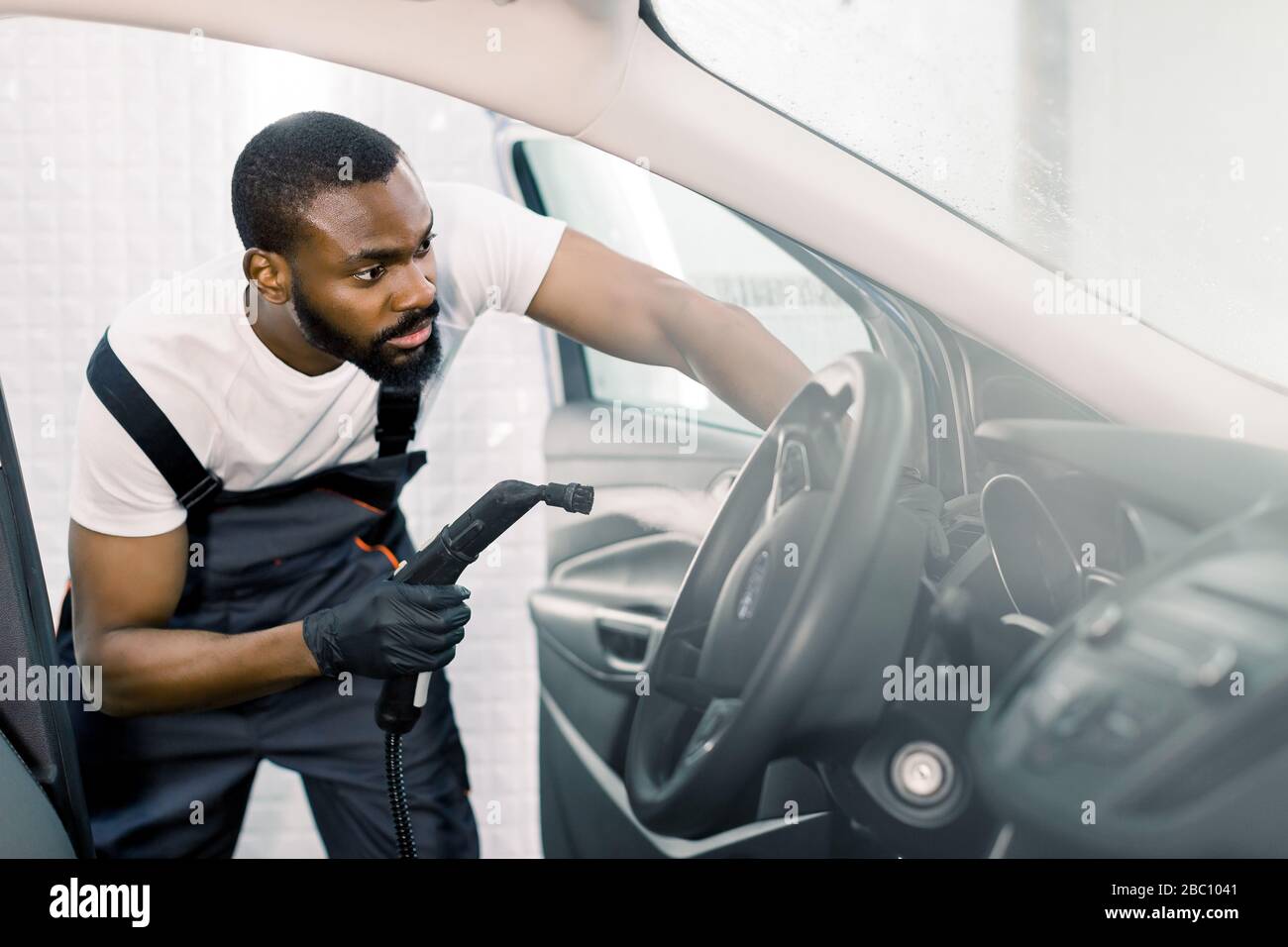 Cleaning of car salon with steam cleaner. Side view of professional