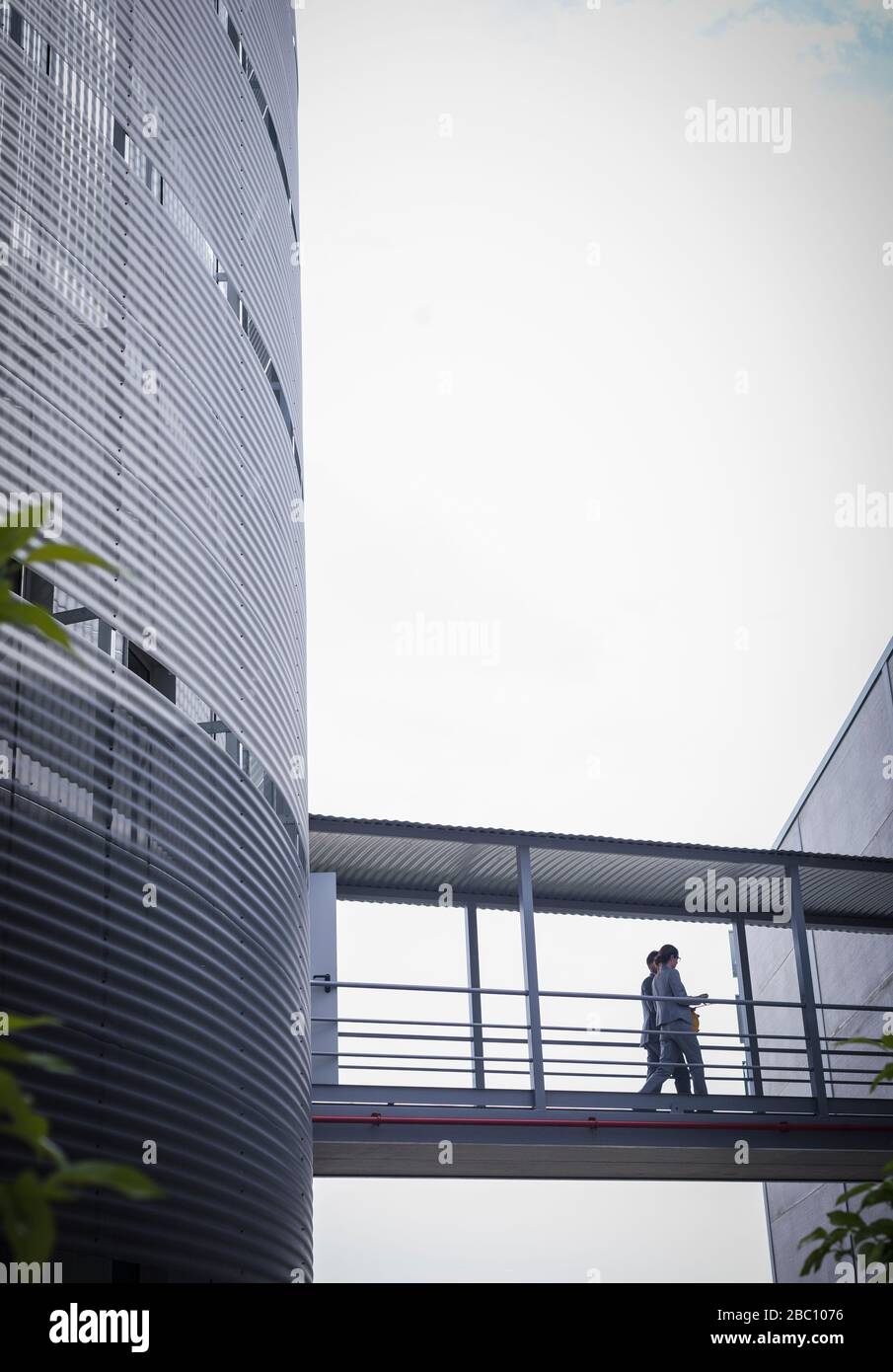 Business people walking on elevated walkway between buildings Stock Photo