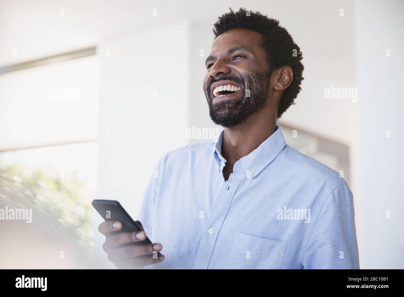 Laughing man using cell phone Stock Photo