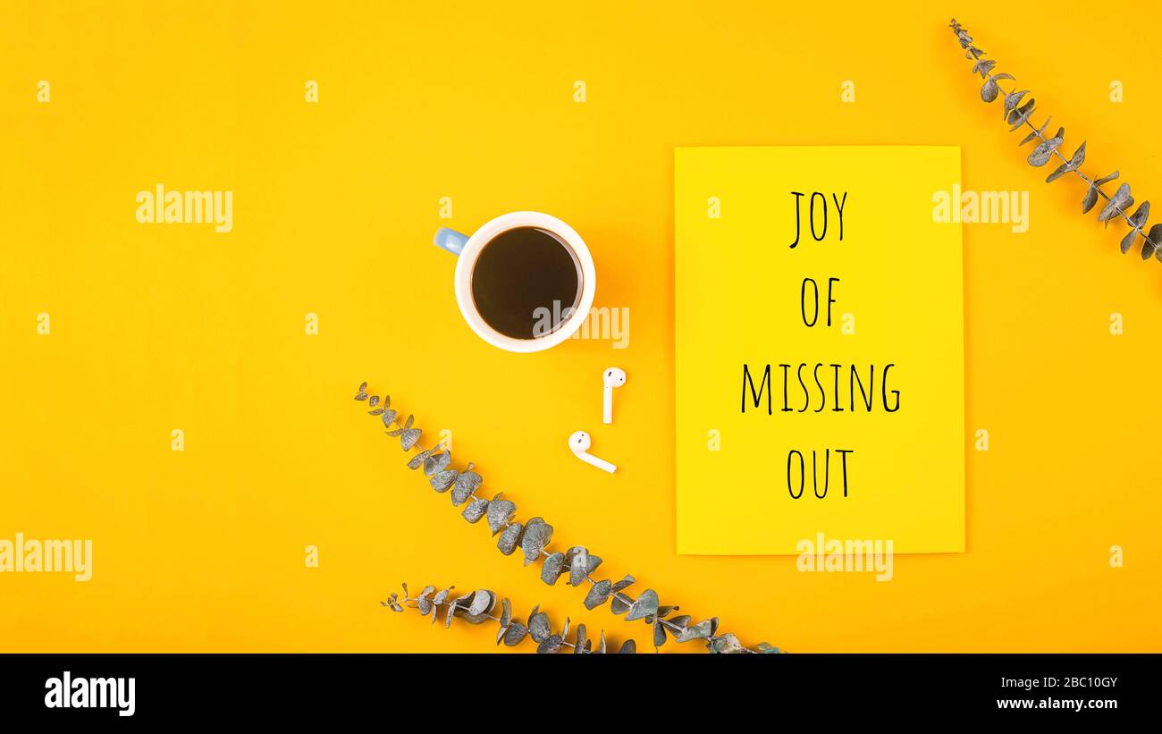Joy of missing out written on yellow background with eucalyptus branches. Stock Photo
