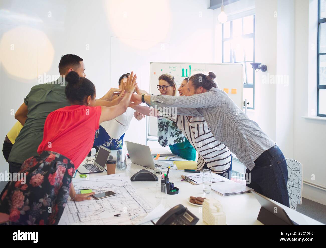Enthusiastic architects high-fiving in conference room meeting Stock Photo