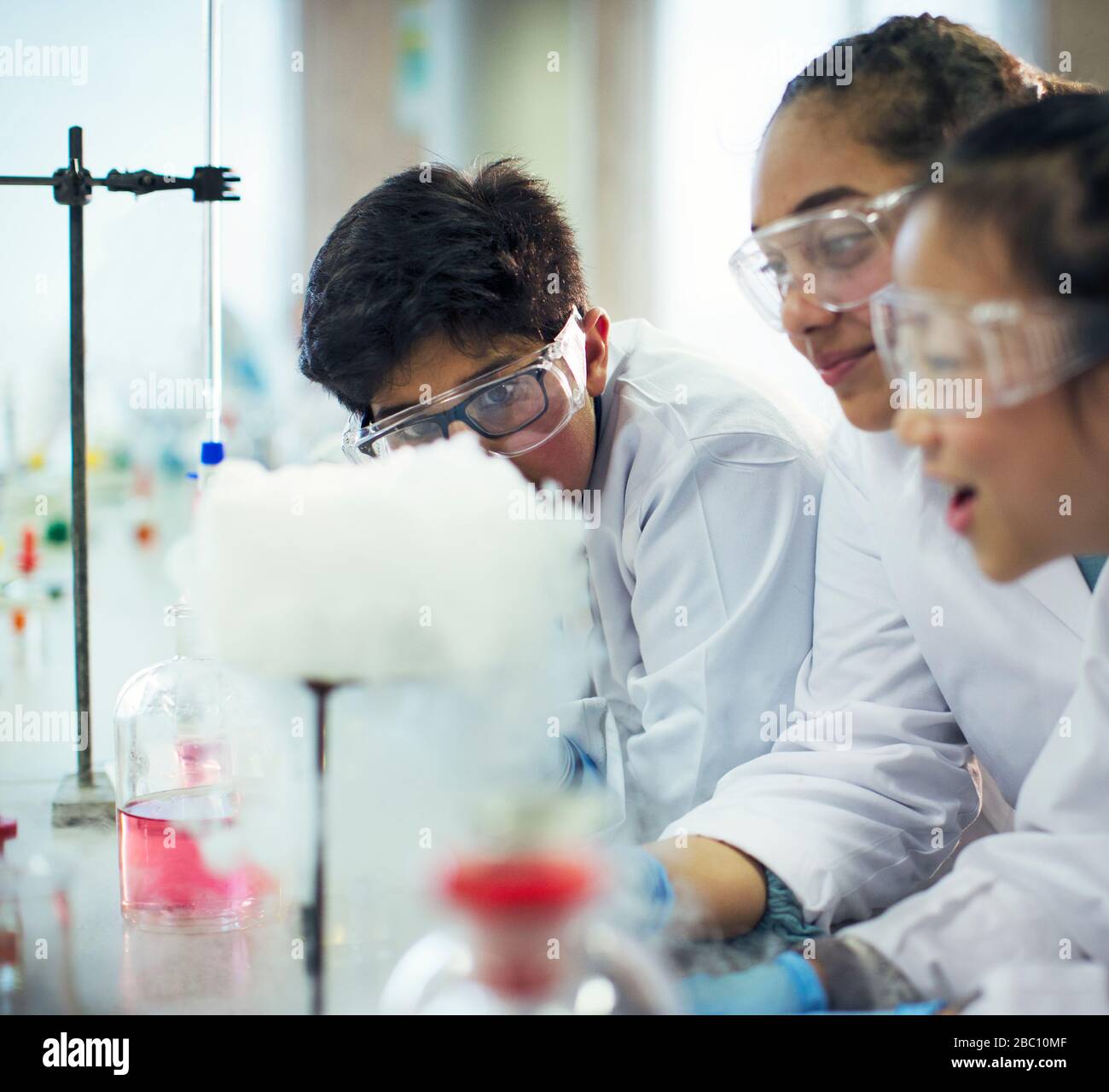 Students watching chemical reaction, conducting scientific experiment in laboratory classroom Stock Photo