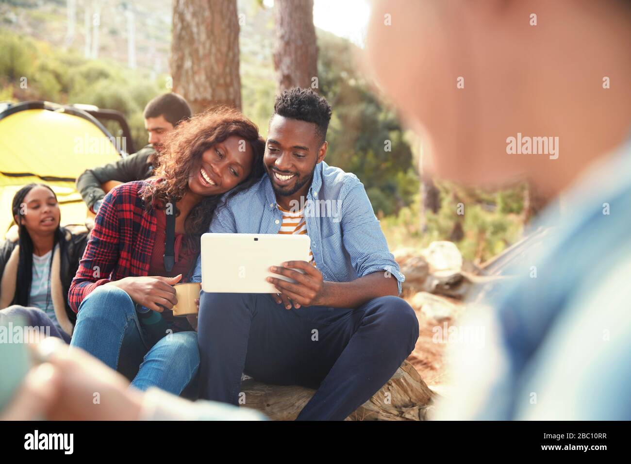 Smiling young couple using digital tablet at campsite Stock Photo