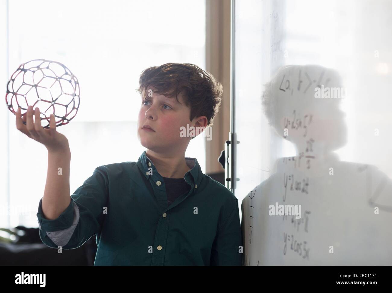 Serious boy student holding molecular structure in classroom Stock Photo