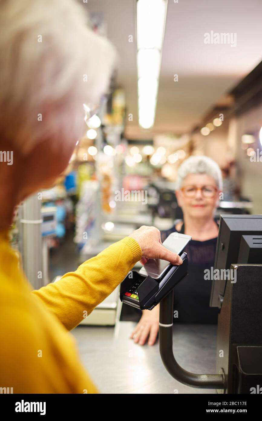 Customer paying with smart phone at supermarket checkout Stock Photo