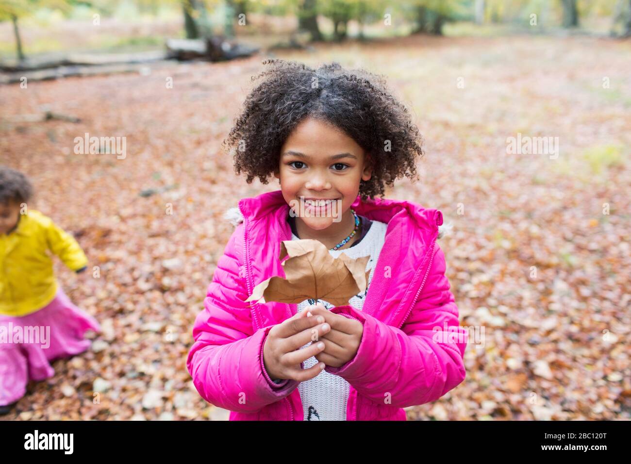 Portrait happy girl holding autumn leaf in woods Stock Photo - Alamy