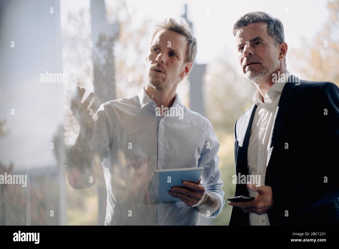 Two businessmen talking at the window Stock Photo - Alamy