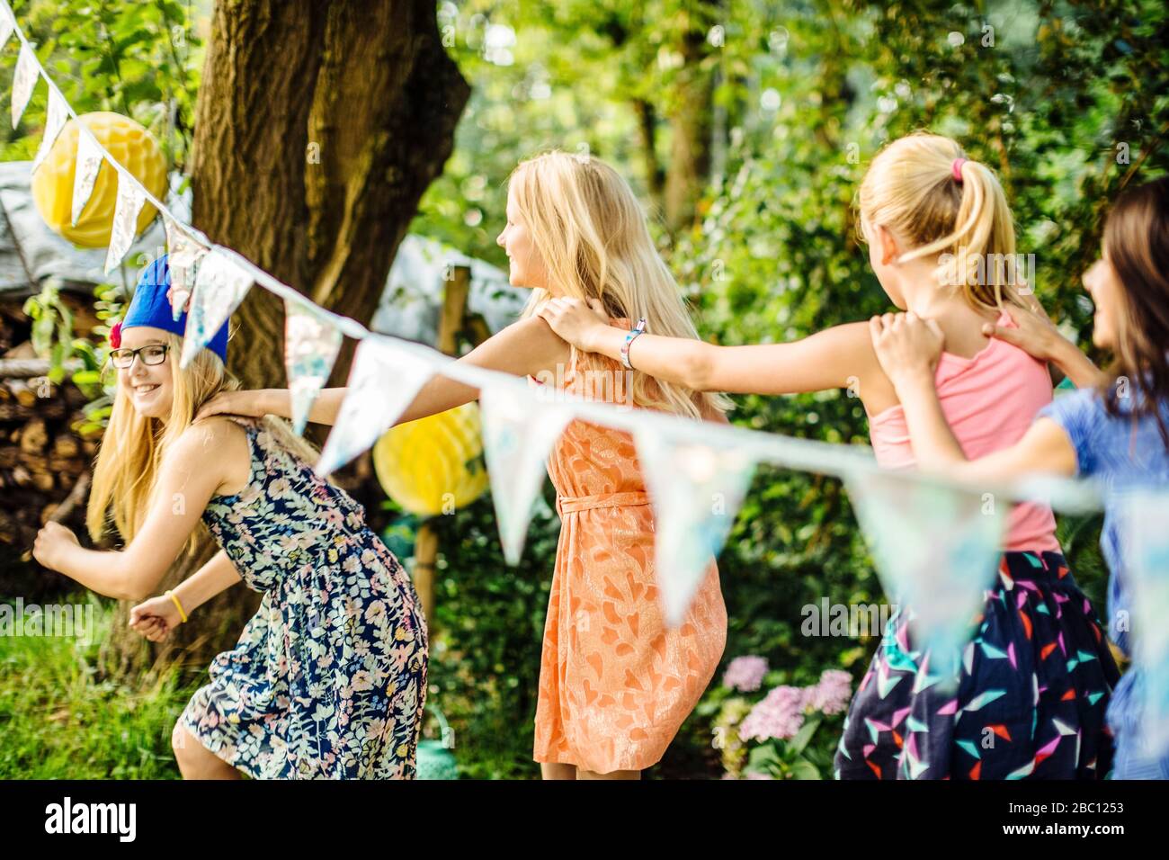 Happy girls doing a conga line on a birthday party outdoors Stock Photo