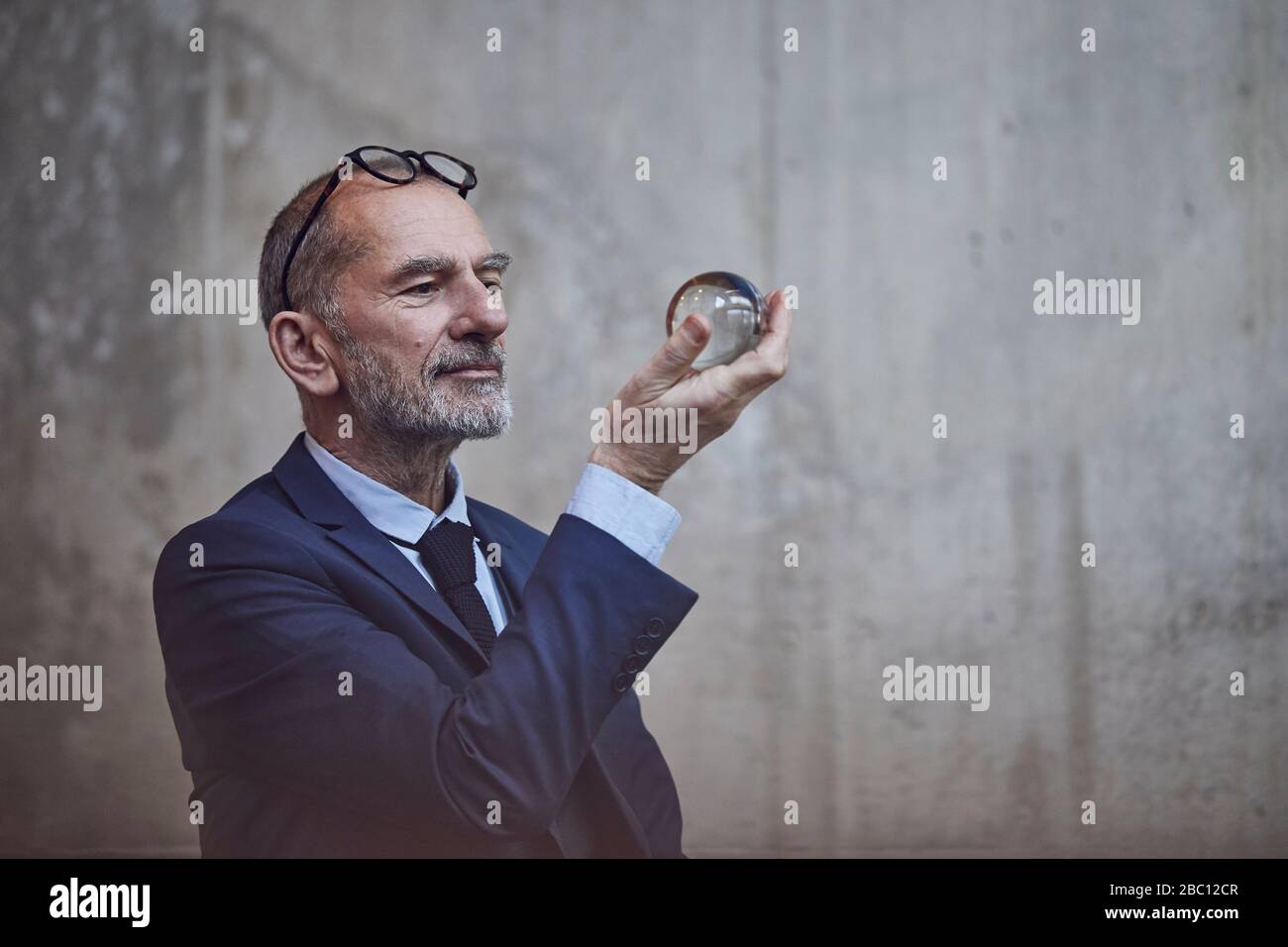 Senior businessman looking at crystal ball Stock Photo - Alamy