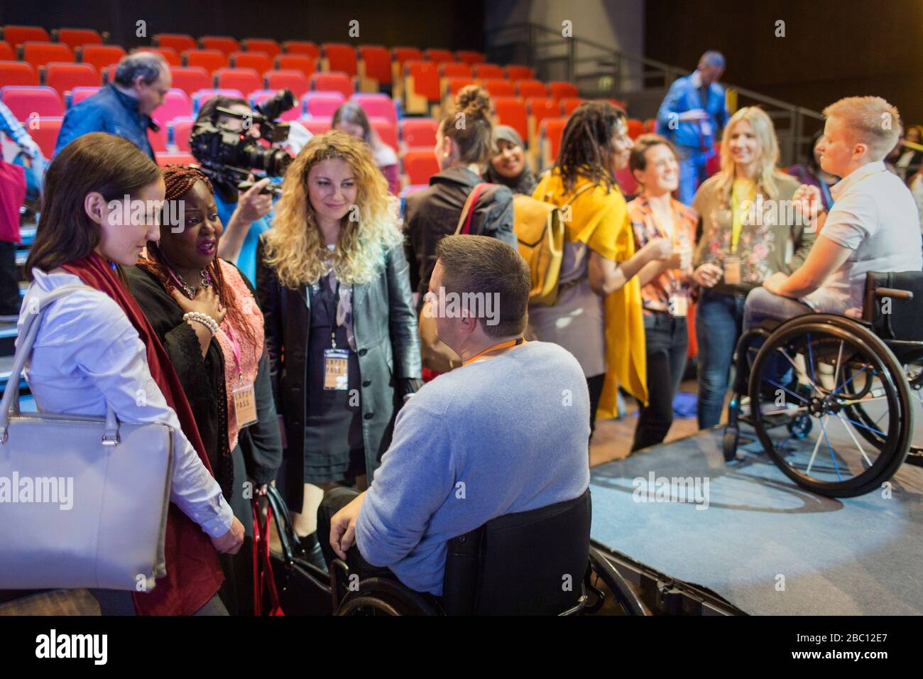 Audience talking to speakers in wheelchairs on stage Stock Photo