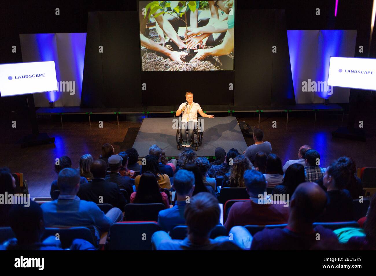 Audience watching female speaker in wheelchair on stage Stock Photo Alamy