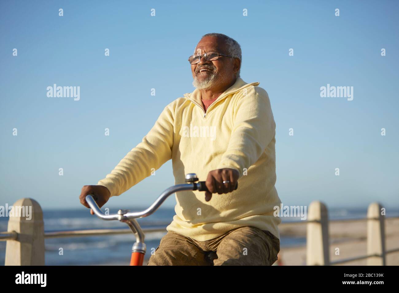 Carefree active senior man tourist bike riding along ocean Stock Photo