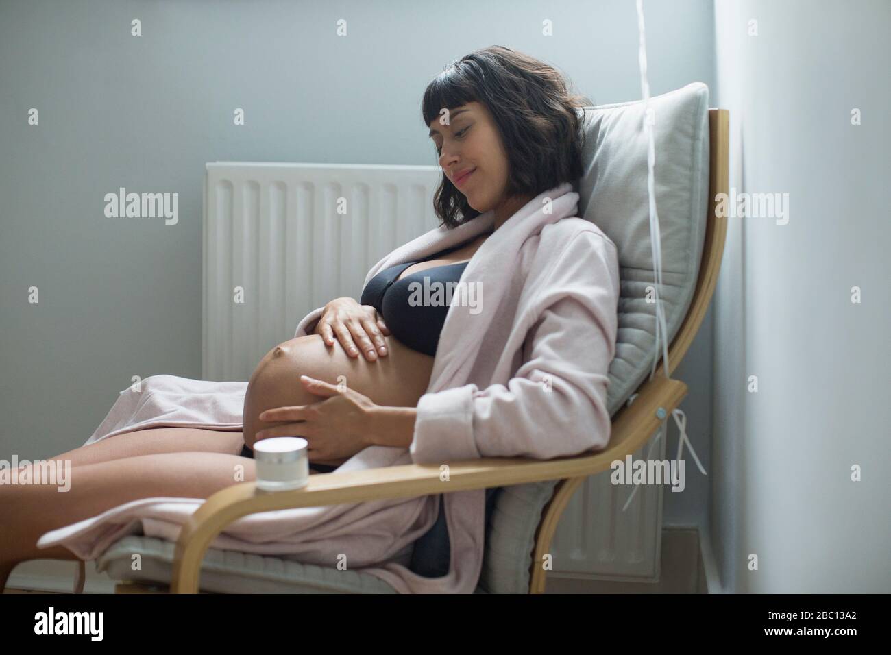 Serene pregnant woman rubbing stomach Stock Photo