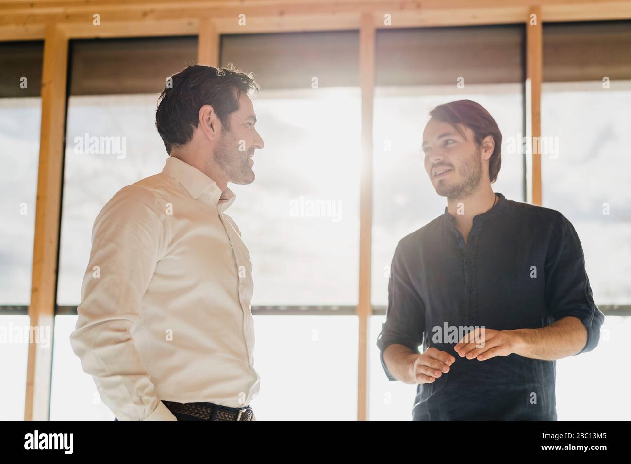 Two businessmen talking at the window in office Stock Photo - Alamy