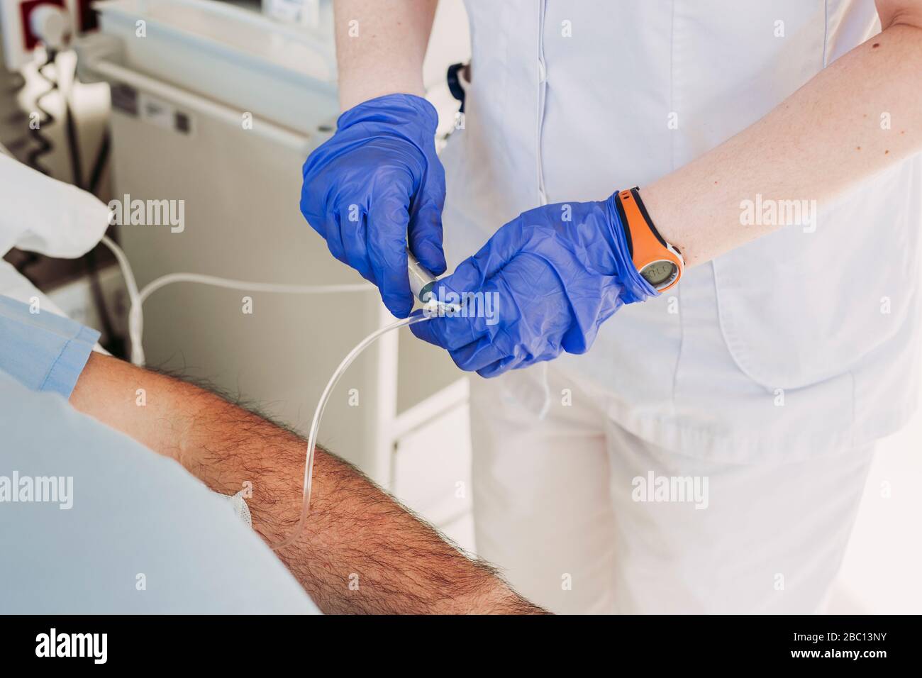 Nurse adjusting iv drip for patient lying in hospital bed Stock Photo