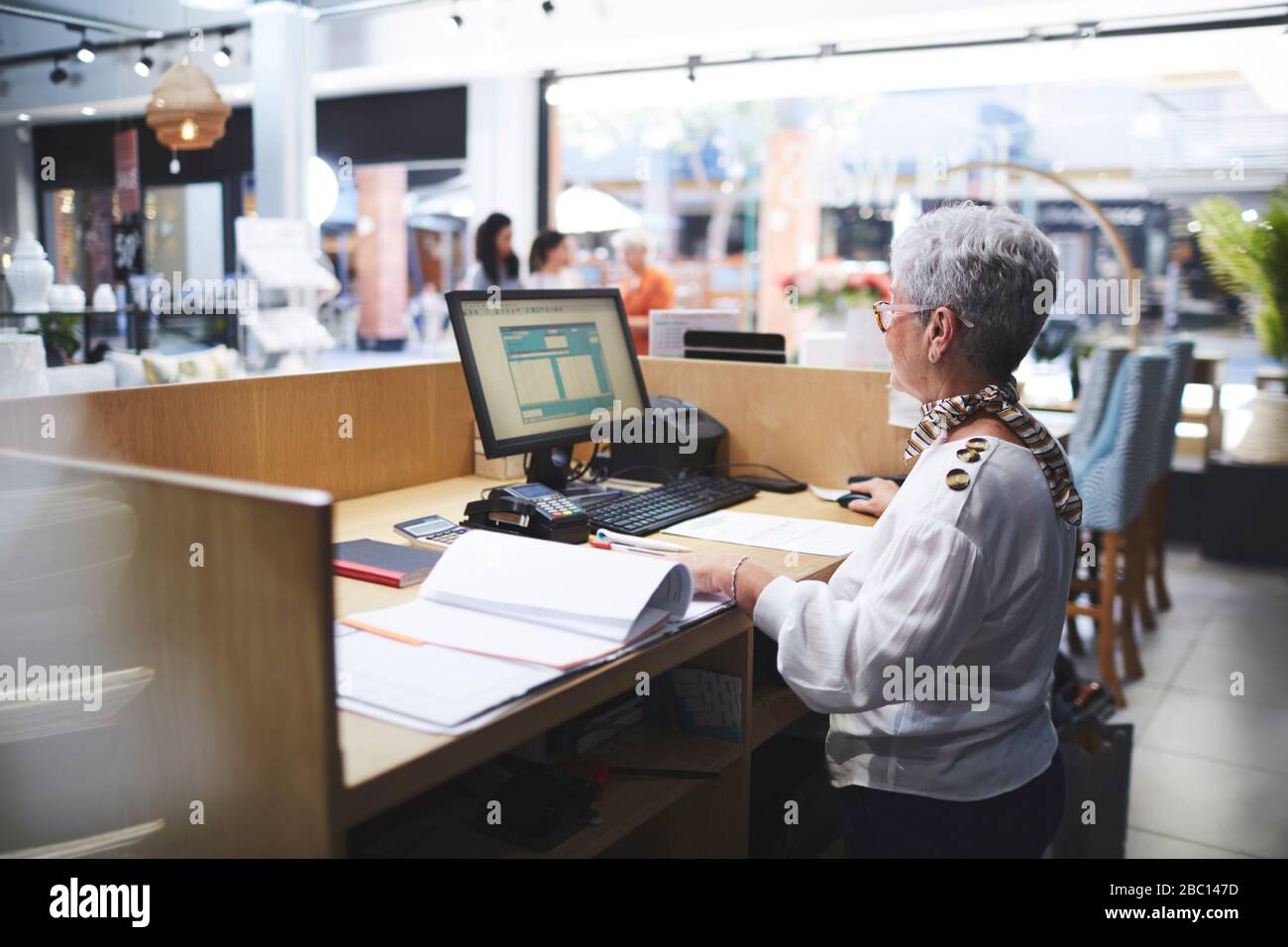 Senior woman working at computer in home decor shop Stock Photo