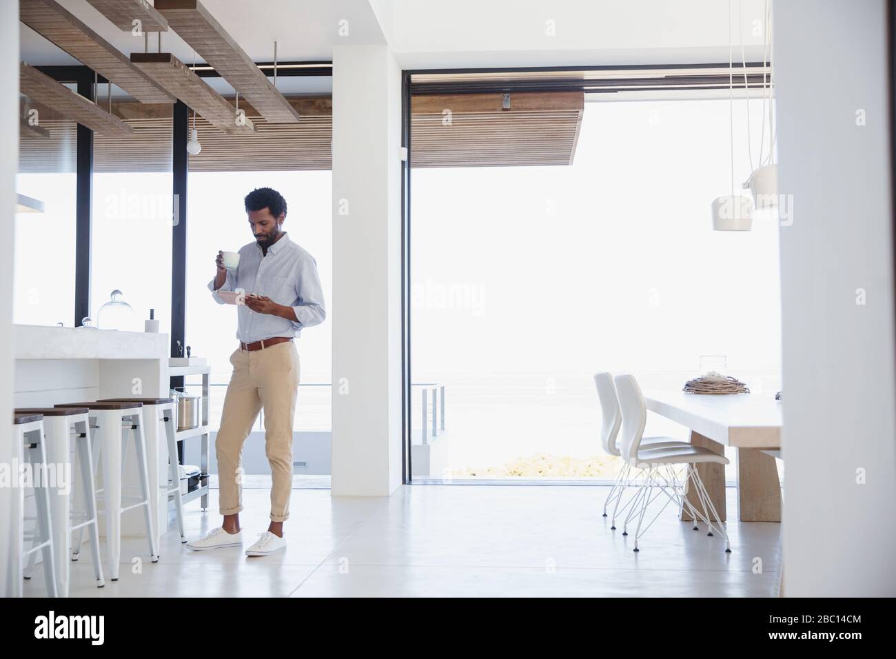 Businessman drinking coffee and using digital tablet in kitchen Stock Photo