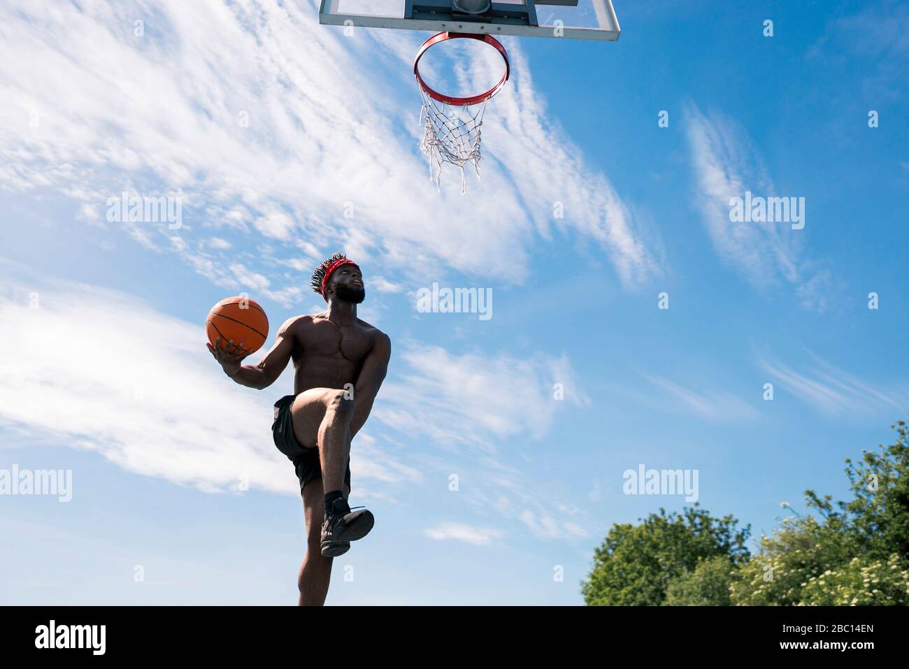 Man playing basketball, dunking Stock Photo