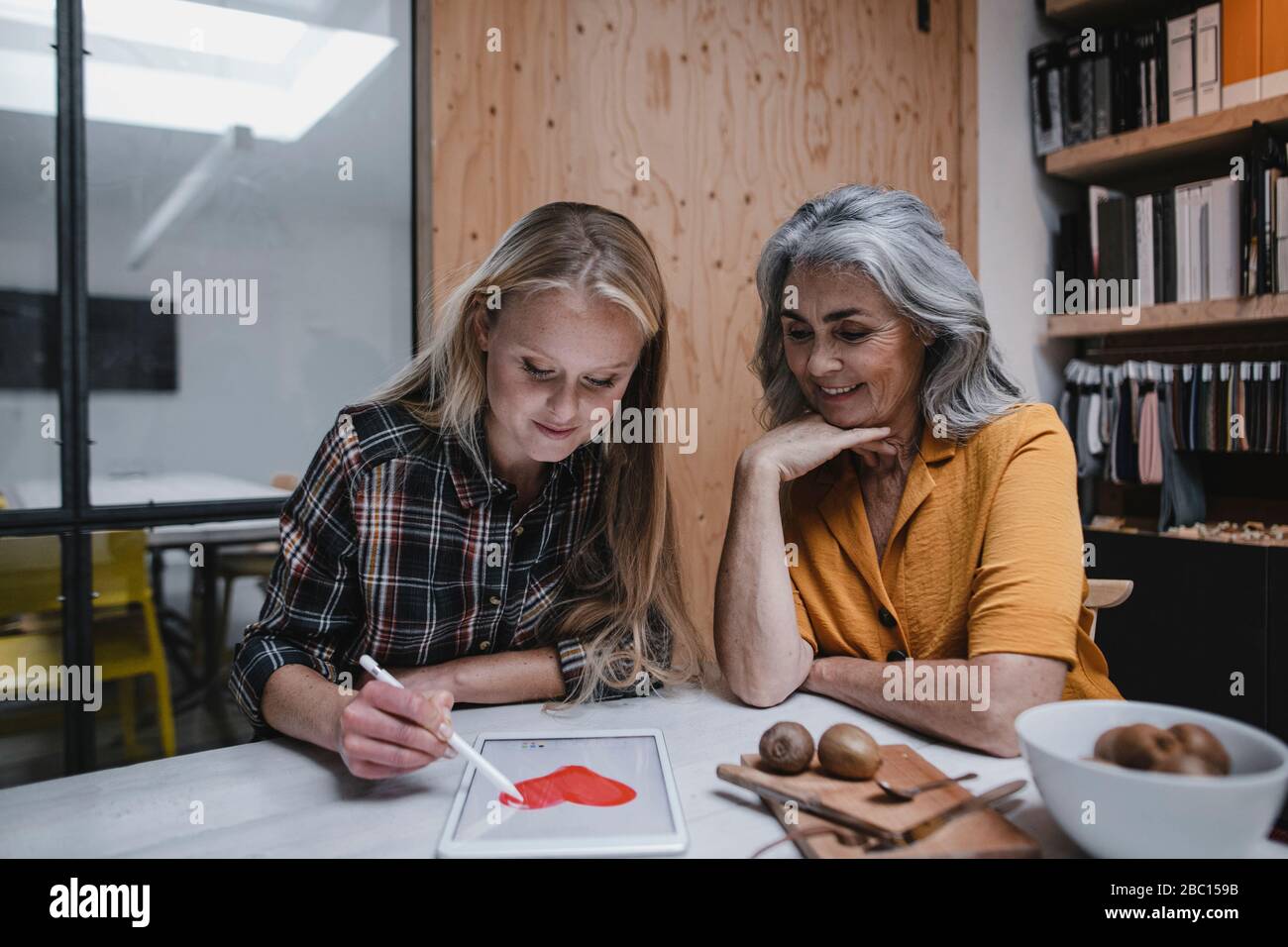Mother and adult daughter drawing heart on tablet screen Stock Photo