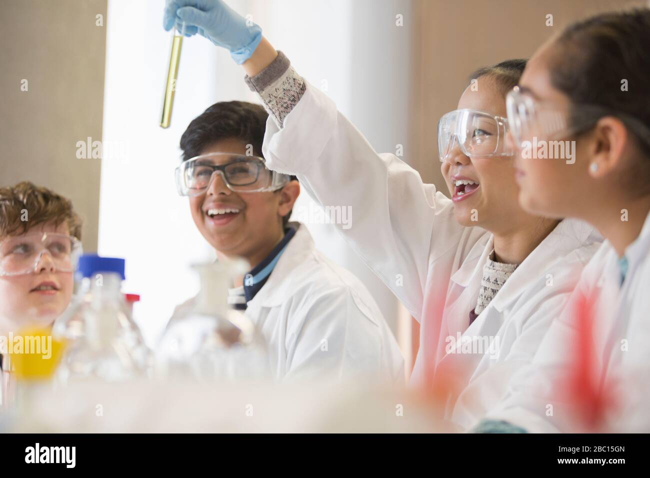 Students examining liquid in test tube, conducting scientific experiment in laboratory classroom Stock Photo