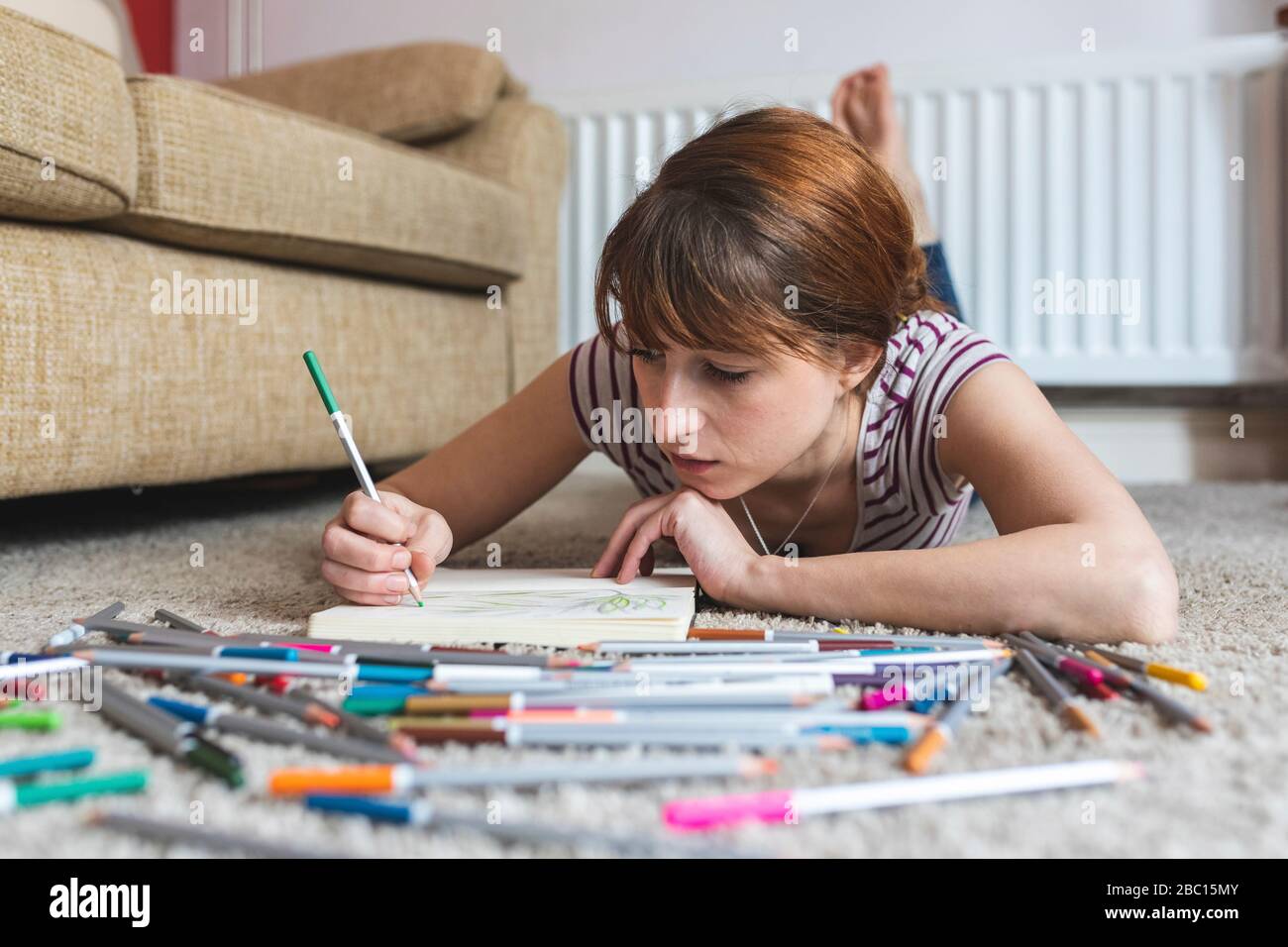Portrait of woman lying on the floor at home drawing Stock Photo - Alamy