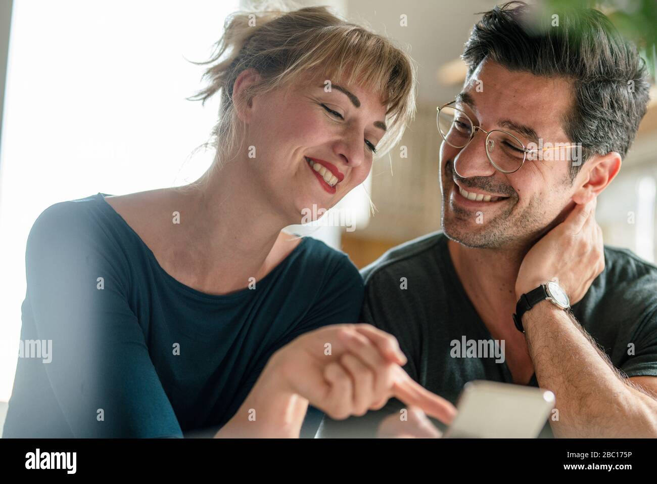 Happy couple using smartphone at home Stock Photo