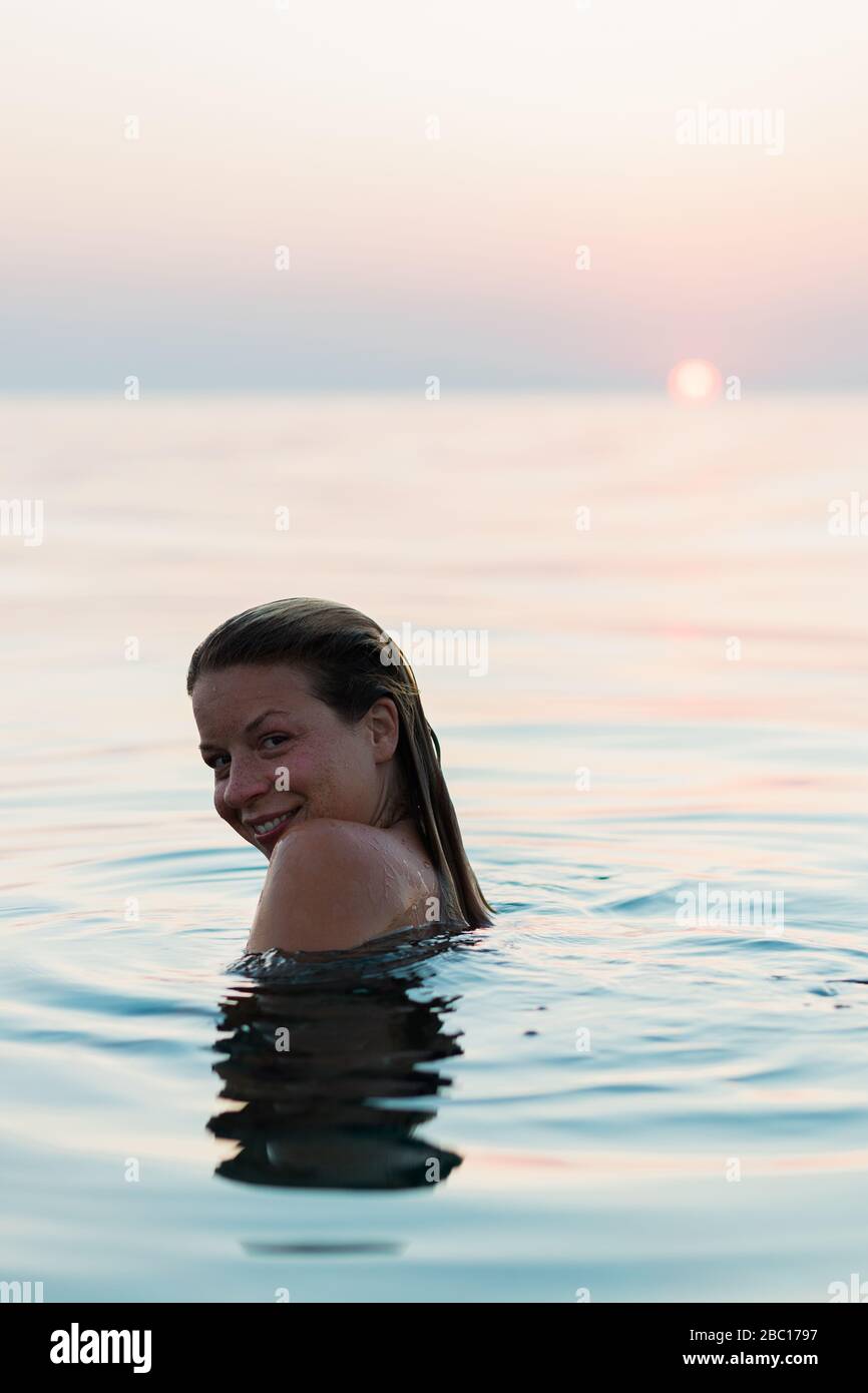 Young woman swimming in the sea in sunset Stock Photo