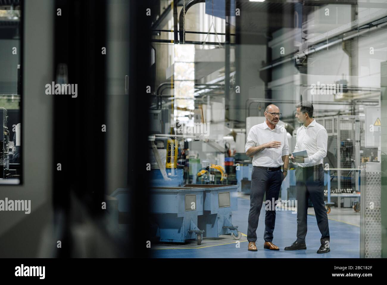 Two businessmen talking in a factory Stock Photo - Alamy