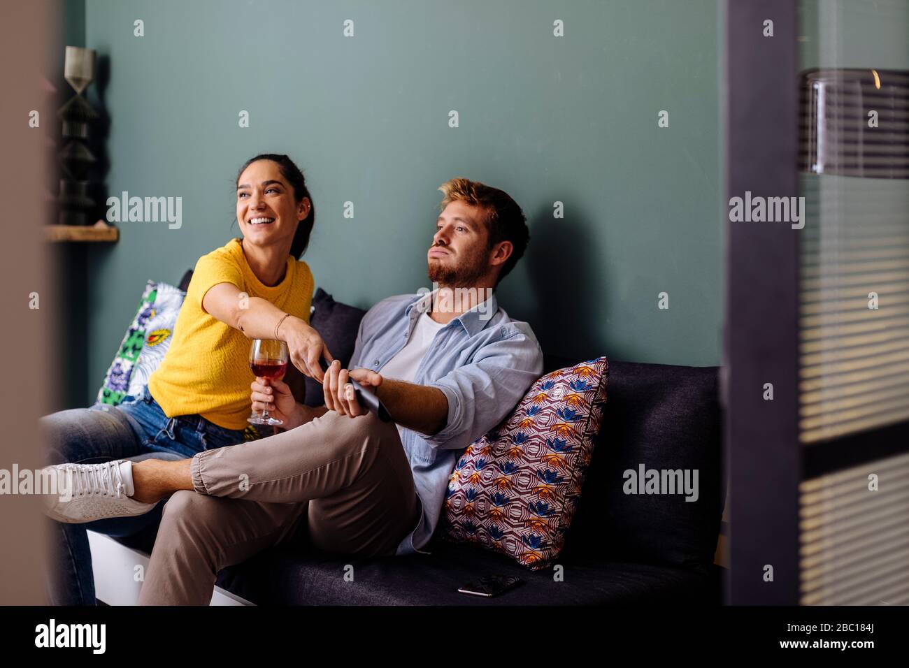 Young couple sitting on the couch at home watching tv Stock Photo