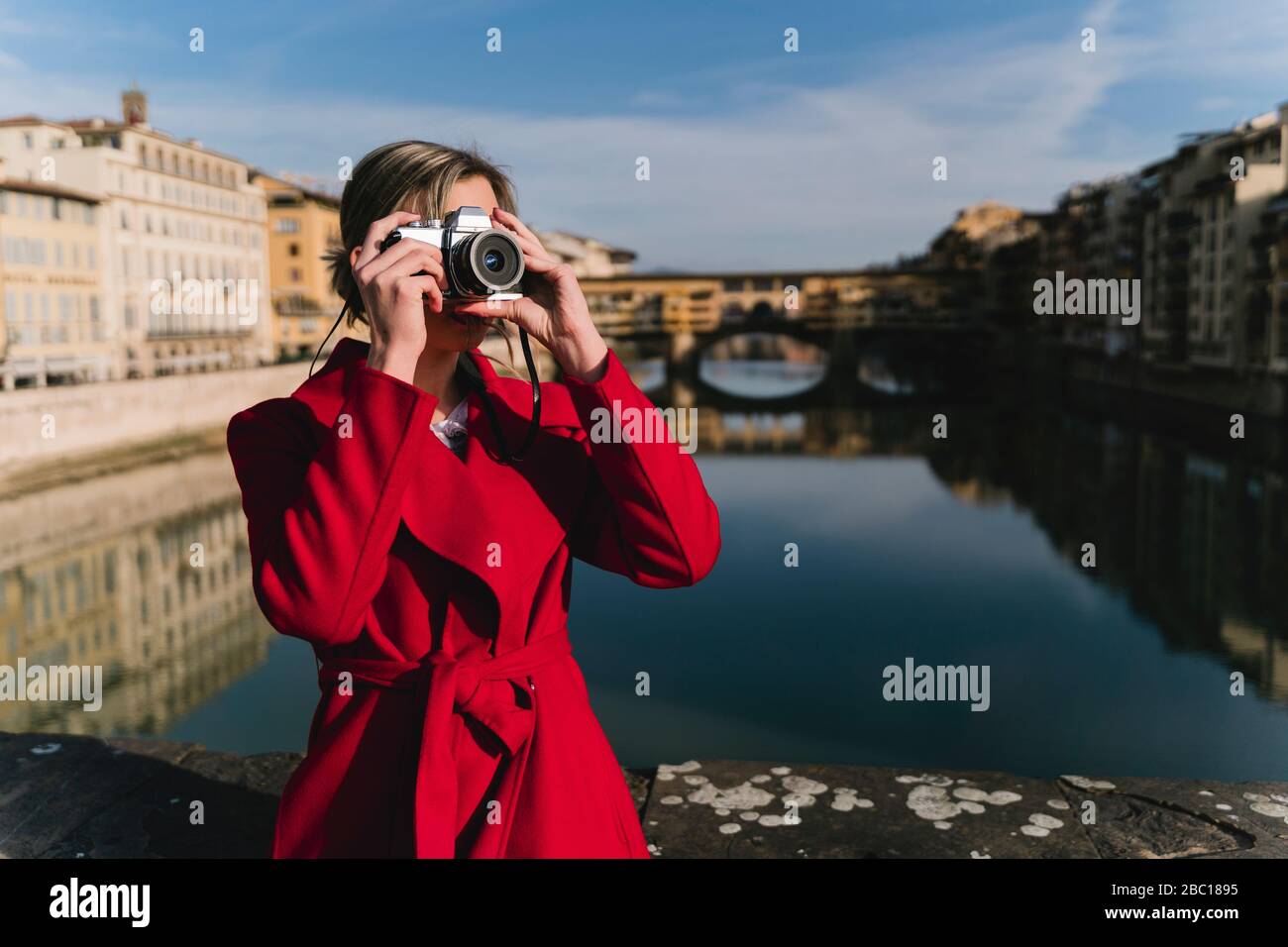 Young woman taking a picture on a bridge above river Arno, Florence, Italy Stock Photo