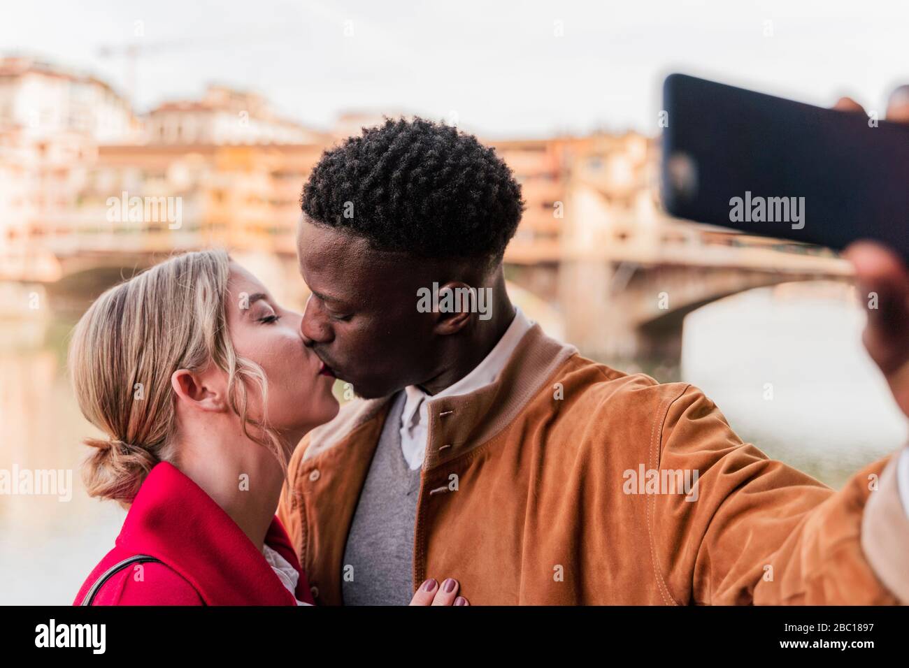 Affectionate young couple kissing and taking a selfie in the city of Florence, Italy Stock Photo