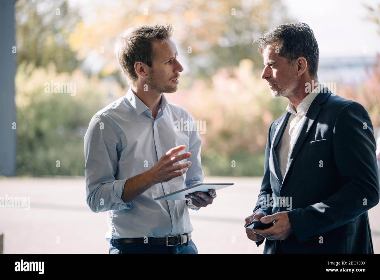 Two businessmen talking at the window Stock Photo - Alamy