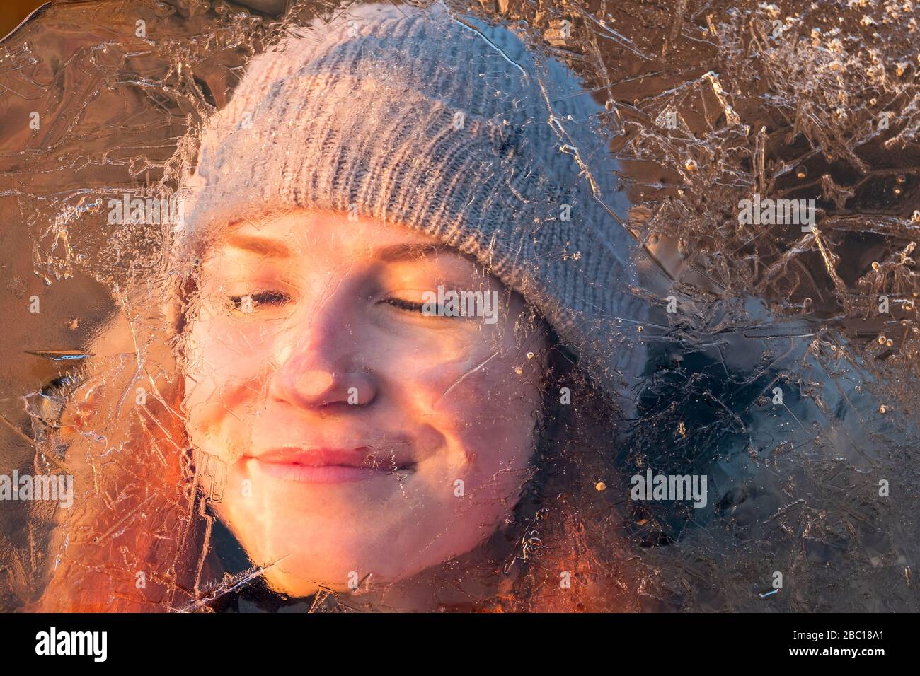 Portrait of smiling teenage girl behind ice-covered surface Stock Photo