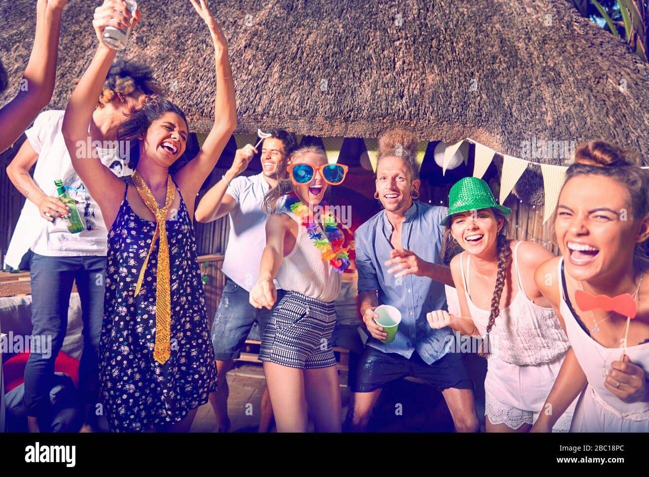 Portrait enthusiastic, playful young friends dancing and laughing at summer party Stock Photo