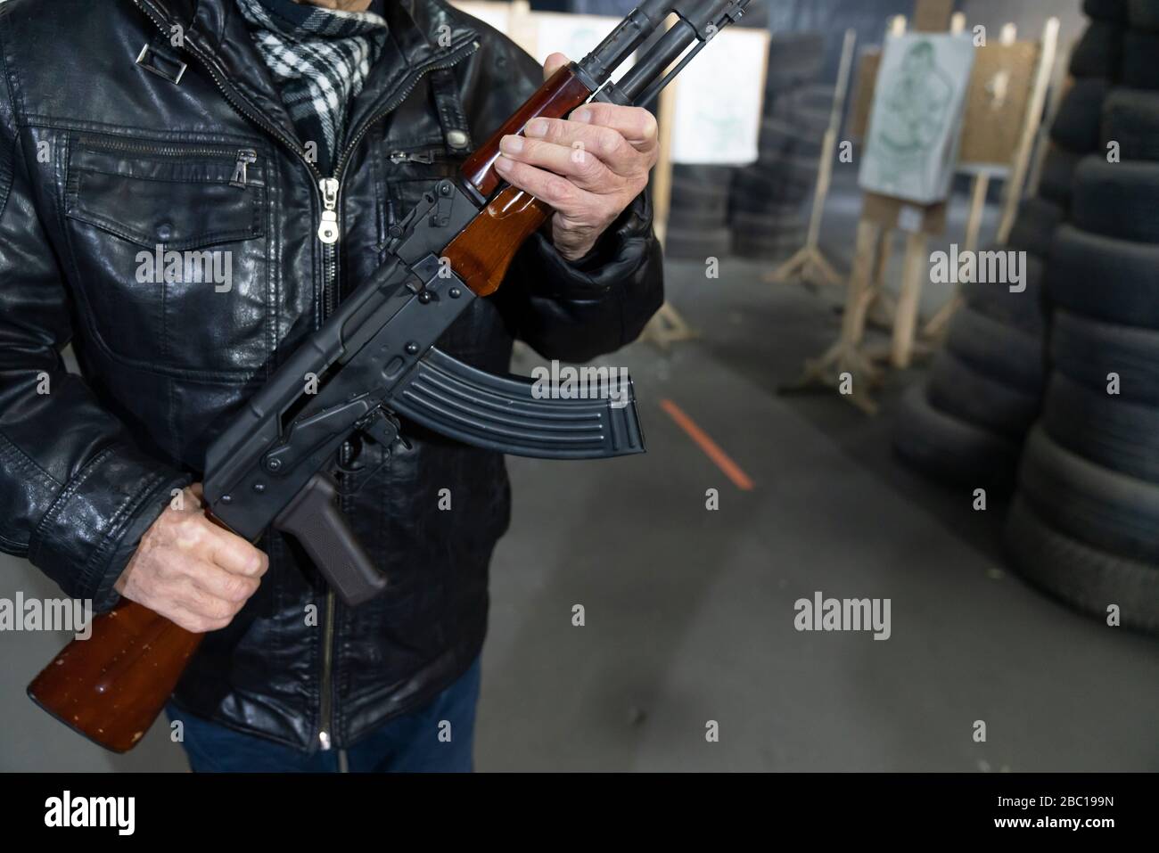 Crop view of senior man with a gun in shooting range Stock Photo