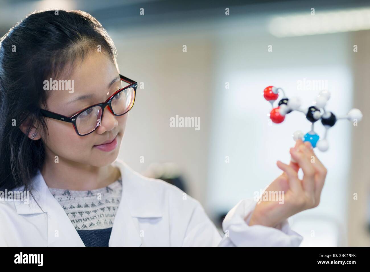 Curious girl student examining molecular structure in classroom Stock Photo