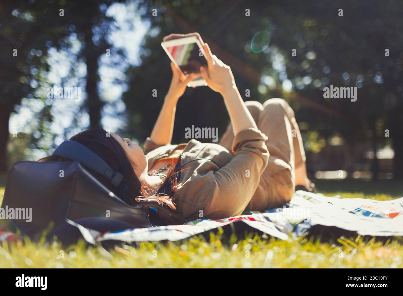 Young woman using digital tablet in sunny summer park Stock Photo