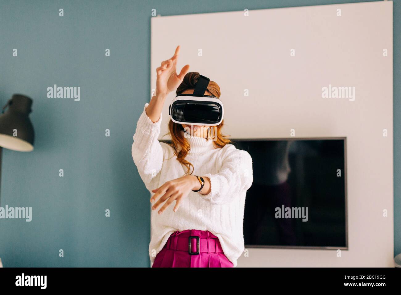 Happy young woman wearing VR glasses at home Stock Photo - Alamy
