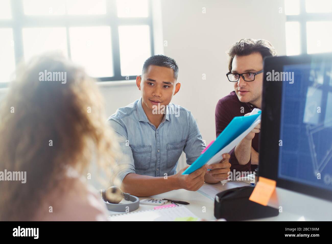 Designers discussing paperwork in office Stock Photo