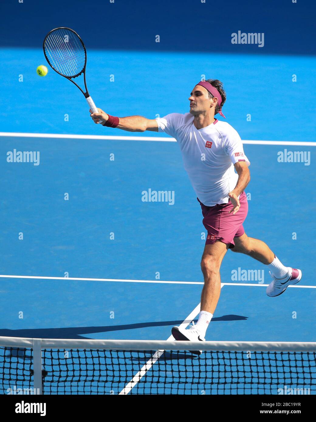 Professional sportsperson jumping mid air tennis net holding tennis