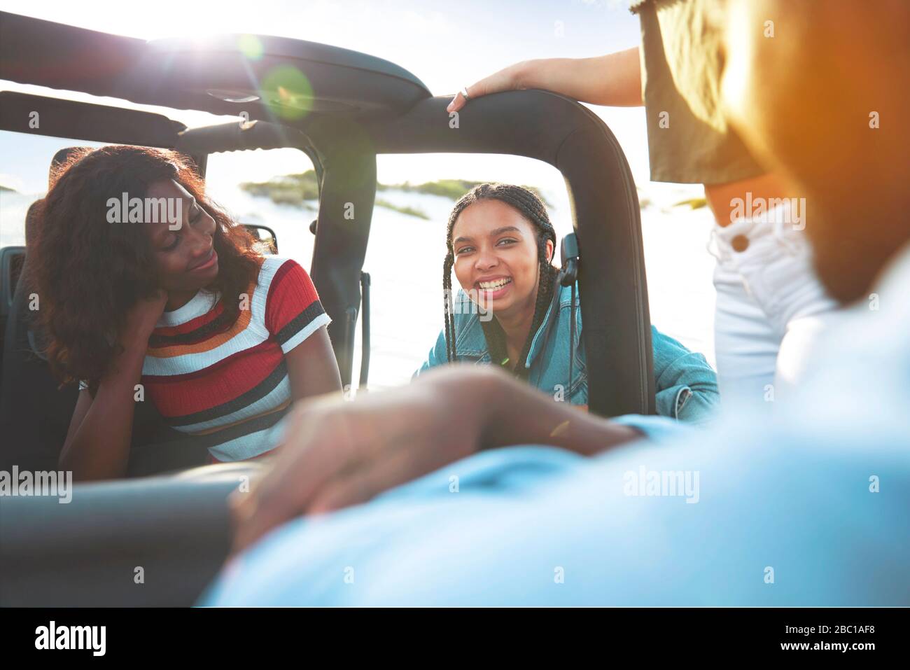 Smiling young friends talking, enjoying road trip in jeep Stock Photo