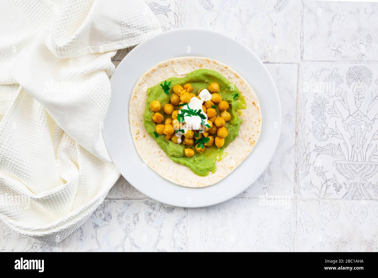 Pita bread with mashed avocados, turmeric chick-peas, yogurt and parsley Stock Photo